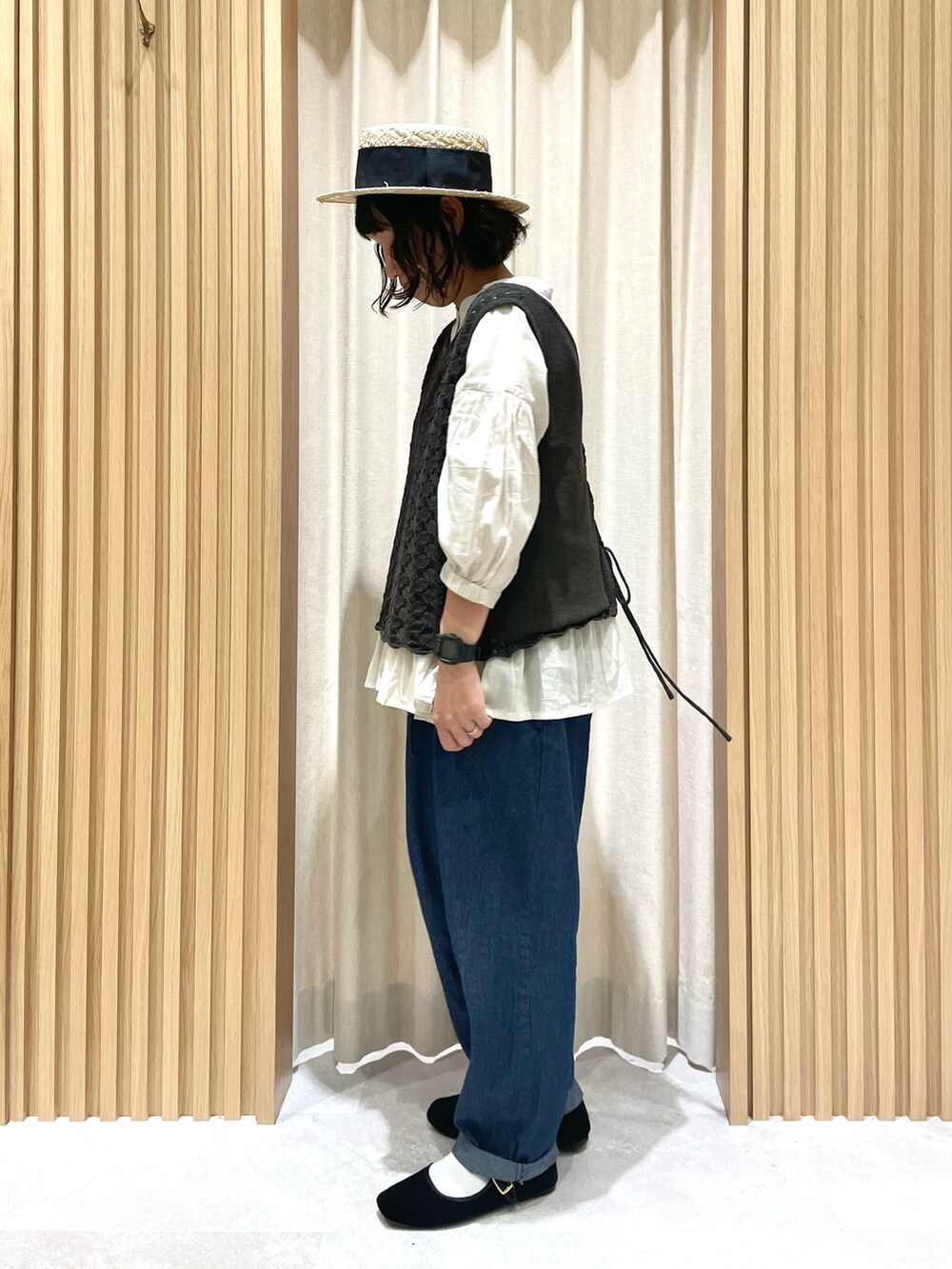 グレー系のベスト、ベージュ系のシャツ/ブラウス、ブルー系のデニムパンツを着用したレディースの夏コーディネートの3枚目の写真