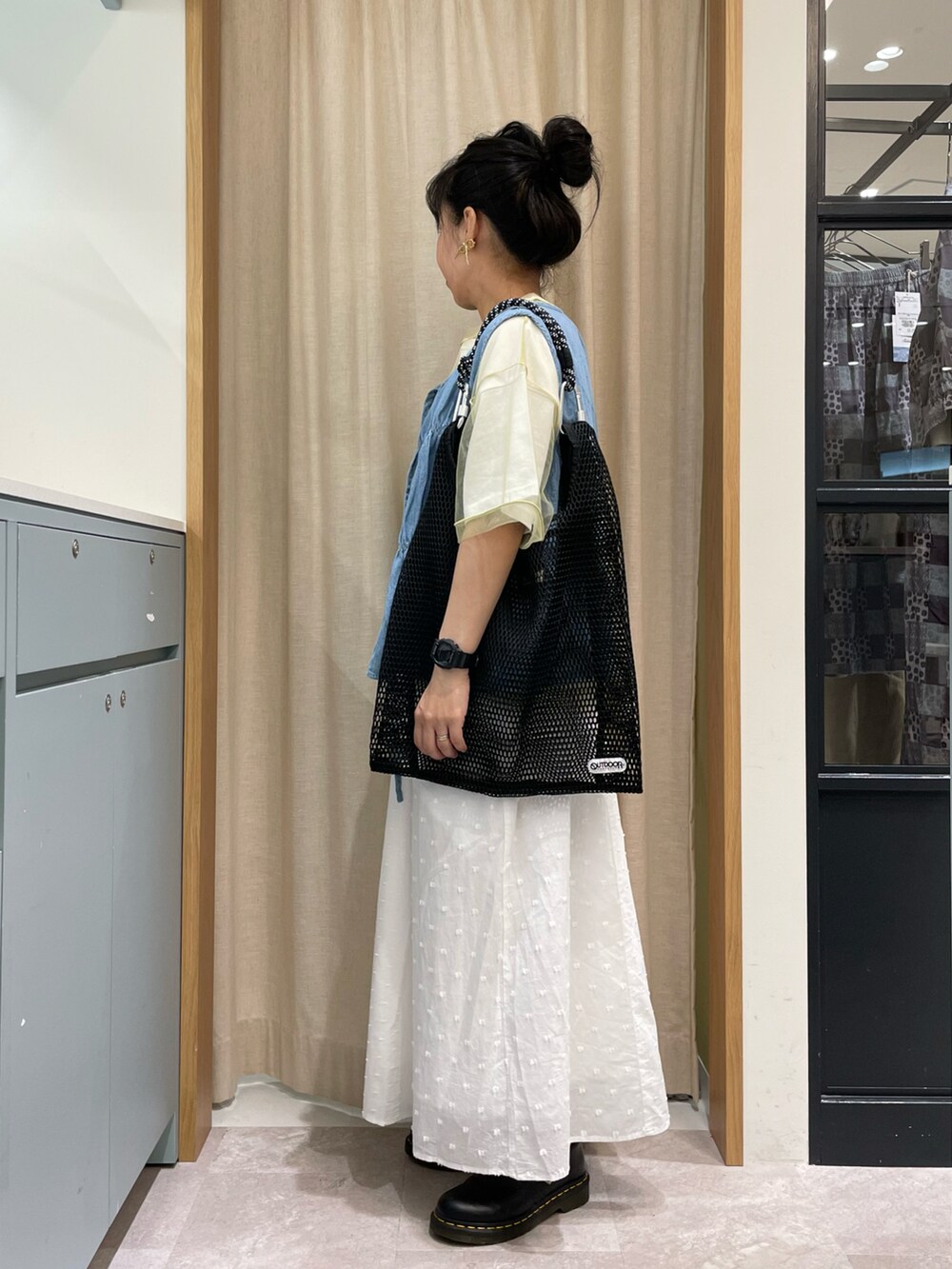 グリーン系のTシャツ/カットソー、ブルー系のベスト、ブラック系のハンドバッグを着用したレディースの春コーディネートの3枚目の写真