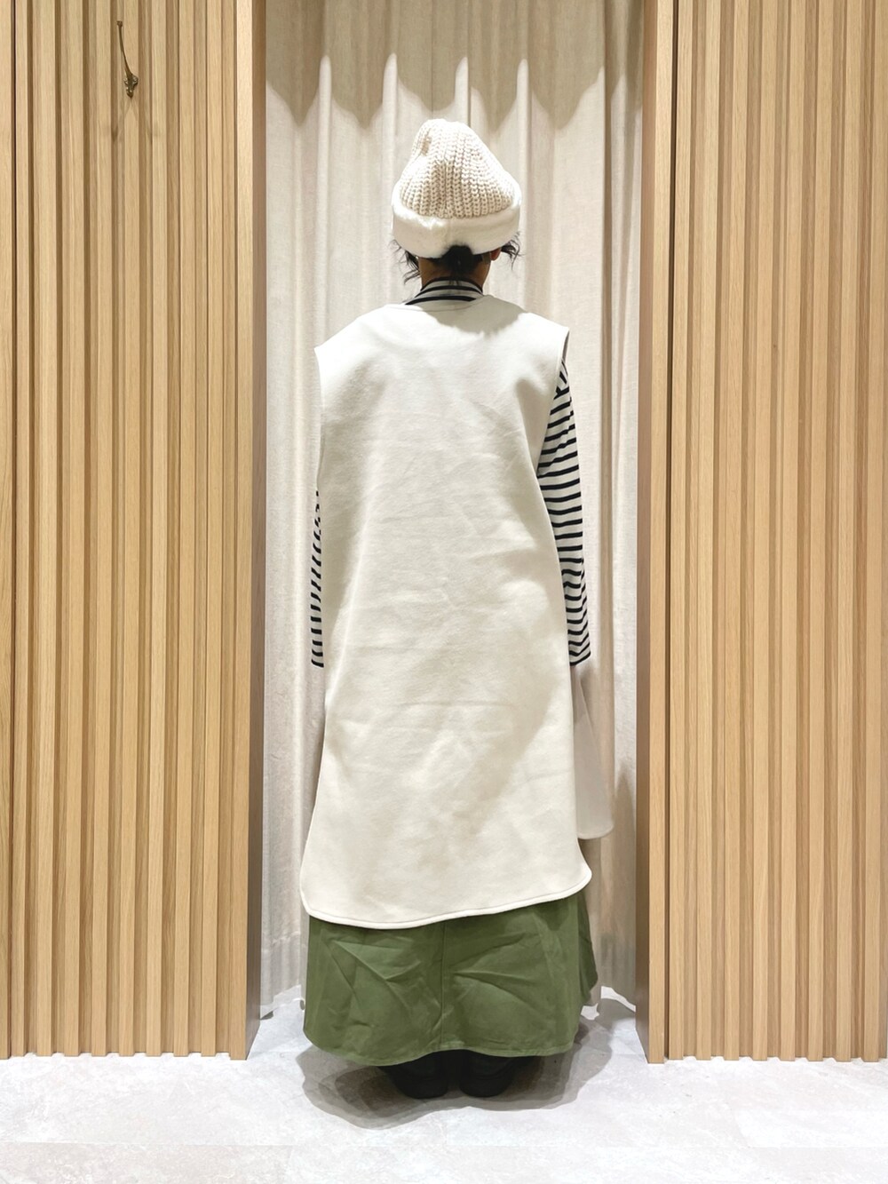 ブルー系のニット/セーター、グリーン系のワンピース、ホワイト系のベストを着用したレディースの冬コーディネートの3枚目の写真