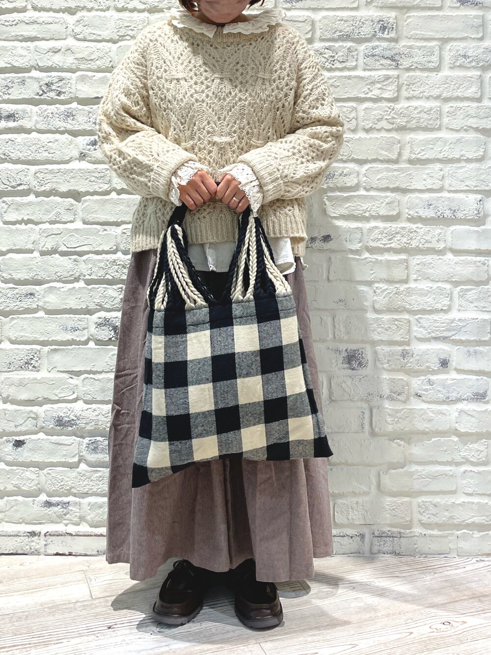 ブラウン系のスカート、ブラック系のハンドバッグ、ブラウン系のローファーを着用したレディースの秋コーディネートの2枚目の写真