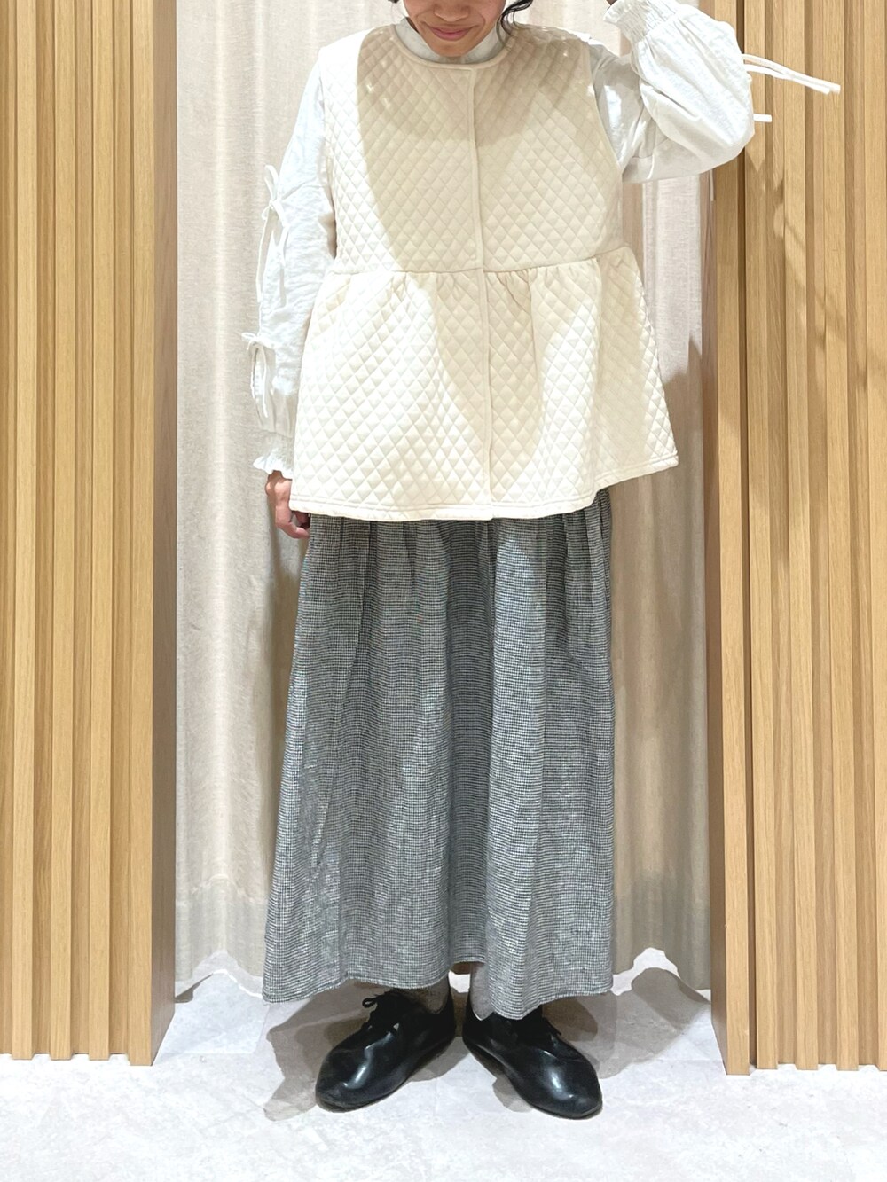 ホワイト系のシャツ/ブラウス、ホワイト系のベスト、グレー系のスカートを着用したレディースの冬コーディネートの2枚目の写真
