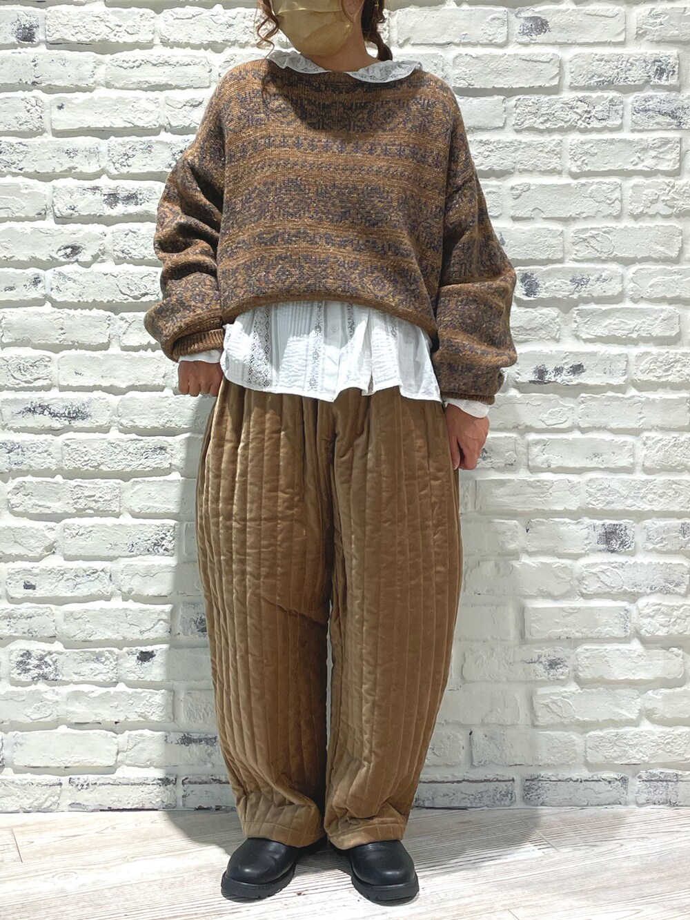 ブラウン系のニット/セーター、ベージュ系のその他パンツ、ブラック系のブーツを着用したレディースの秋コーディネートの2枚目の写真