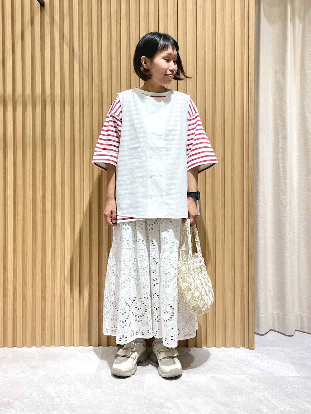 ホワイト系のベスト、レッド系のTシャツ/カットソー、ホワイト系のスカートを着用したレディースの春コーディネートの2枚目の写真