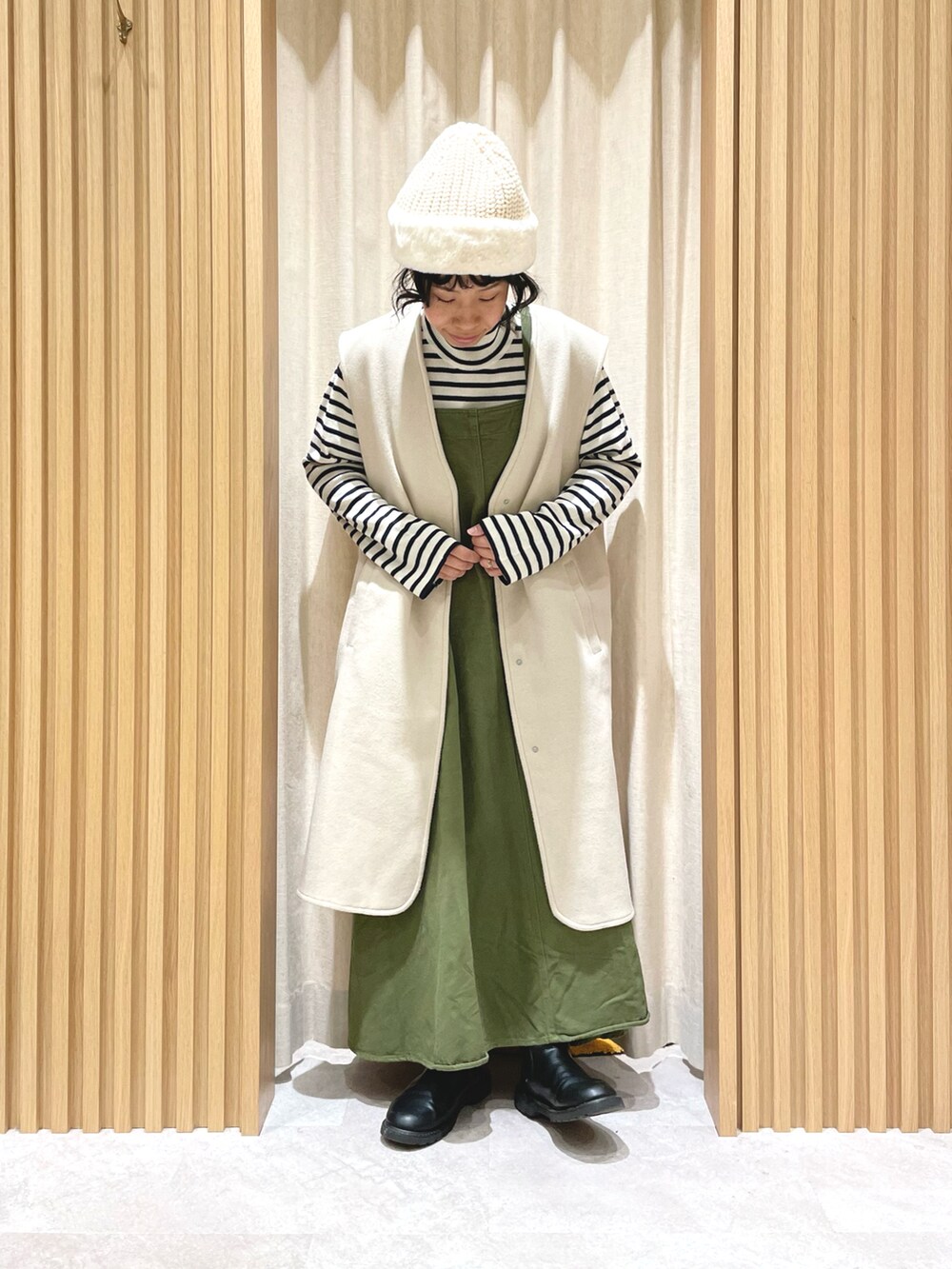 ブルー系のニット/セーター、グリーン系のワンピース、ホワイト系のベストを着用したレディースの冬コーディネートの2枚目の写真