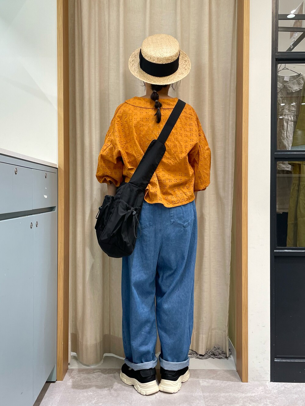 オレンジ系のシャツ/ブラウス、ホワイト系のTシャツ/カットソー、ブラック系のハンドバッグを着用したレディースの夏コーディネートの2枚目の写真