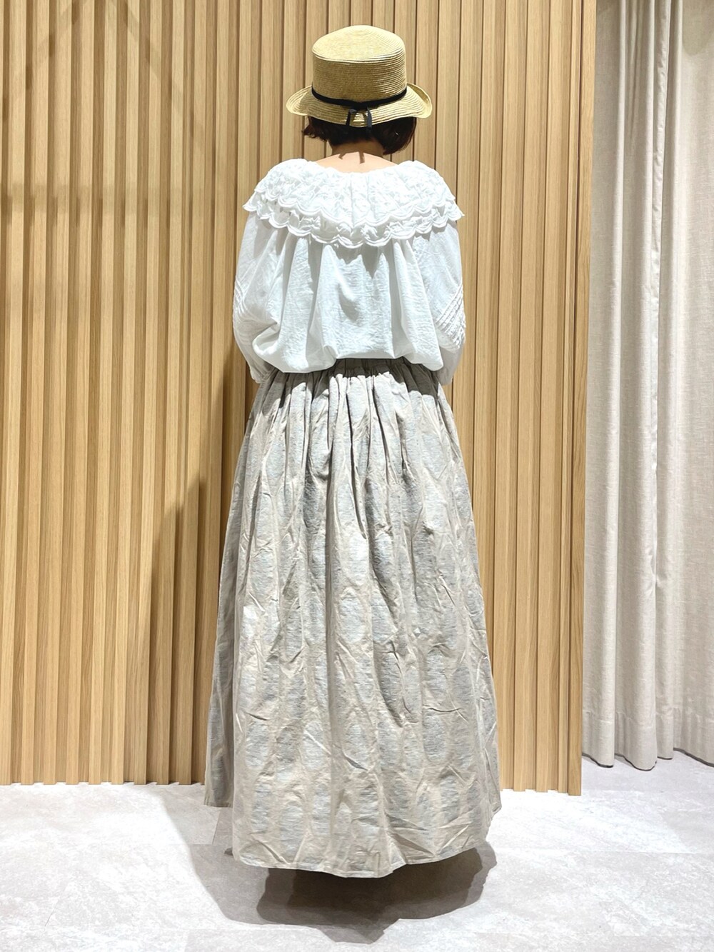 ホワイト系のチュニック、ベージュ系のスカート、グレー系のハンドバッグを着用したレディースの夏コーディネートの2枚目の写真