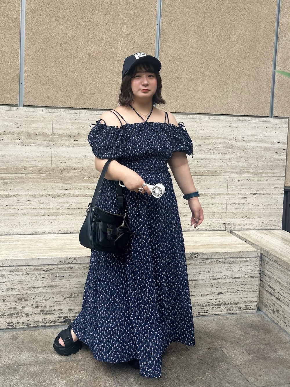 ブルー系のワンピース、ブラック系のサンダル、ブラック系のショルダーバッグを着用したレディースの夏コーディネートの2枚目の写真
