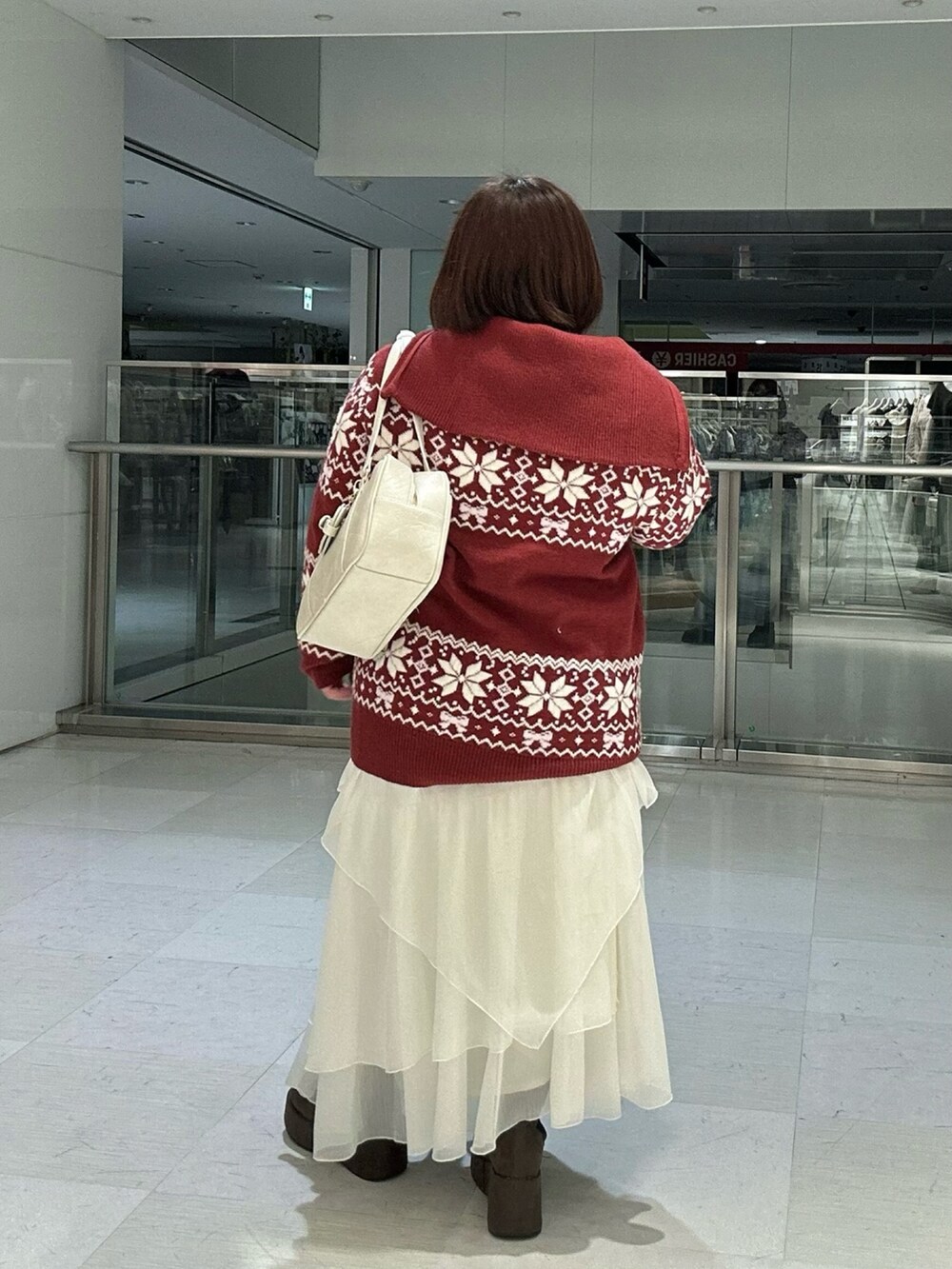 ホワイト系のスカート、ブラウン系のブーツ、レッド系のニット/セーターを着用したレディースの冬コーディネートの6枚目の写真