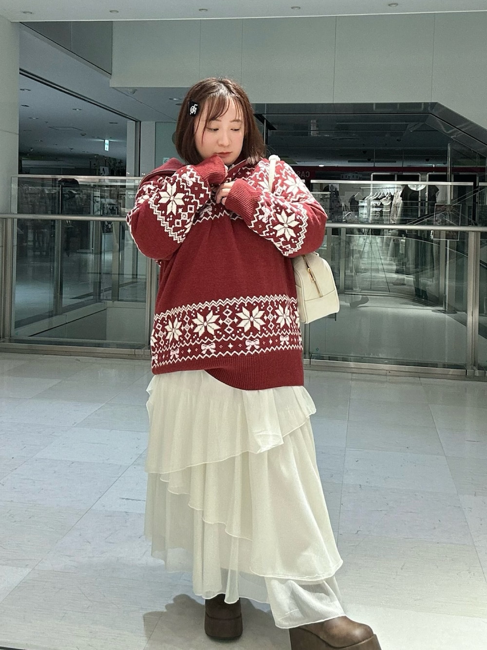 ホワイト系のスカート、ブラウン系のブーツ、レッド系のニット/セーターを着用したレディースの冬コーディネートの5枚目の写真