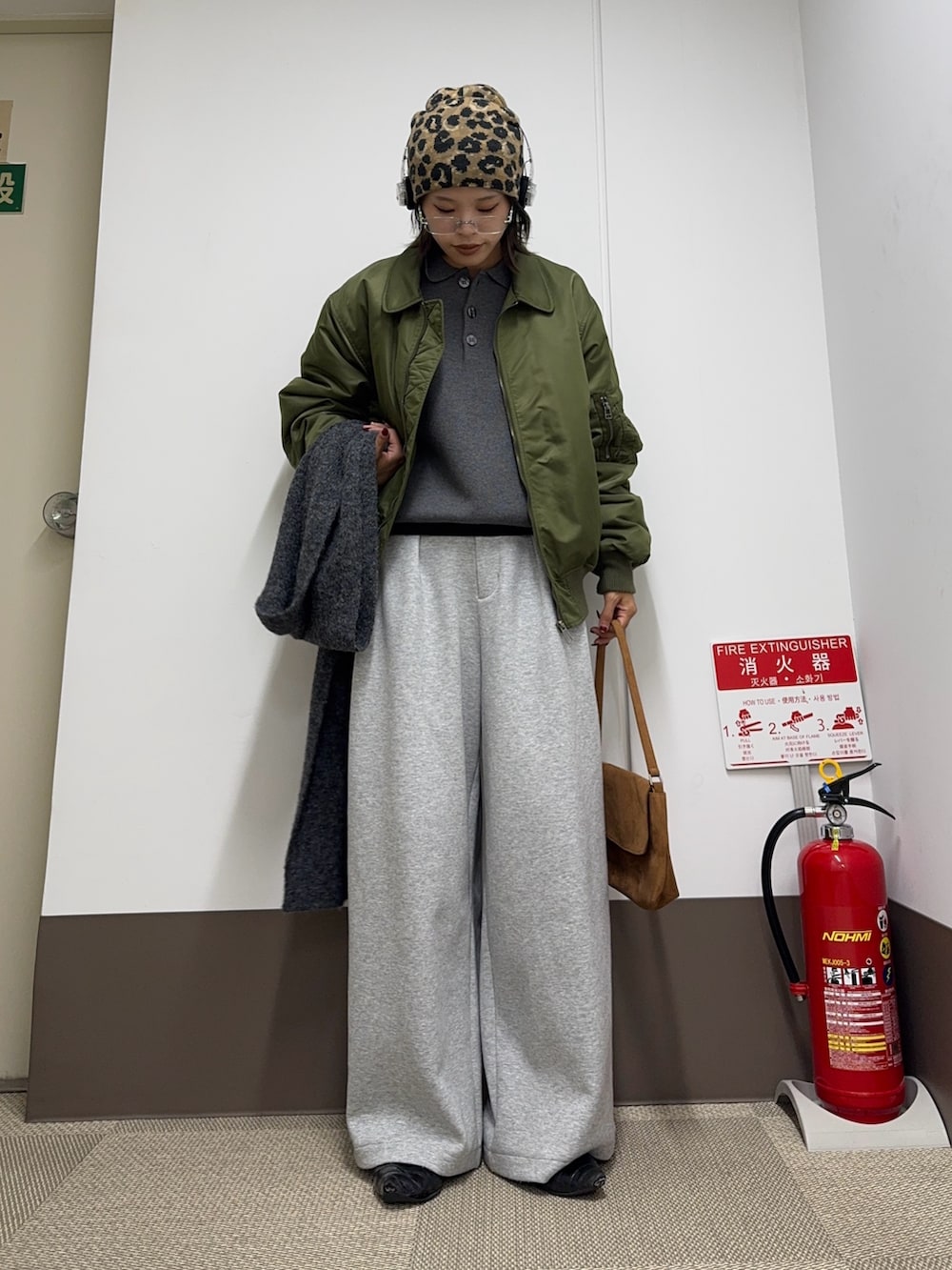 グリーン系のMA-1、グレー系のニット/セーター、イエロー系のハンドバッグを着用したレディースの秋コーディネートの2枚目の写真