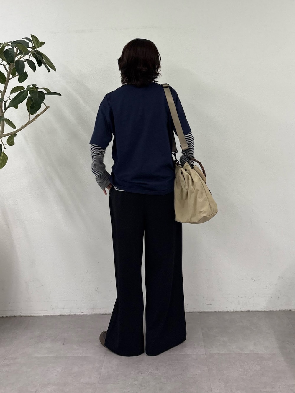 ブルー系のTシャツ/カットソー、ブラック系のスラックス、ベージュ系のトートバッグを着用したレディースの春コーディネートの4枚目の写真