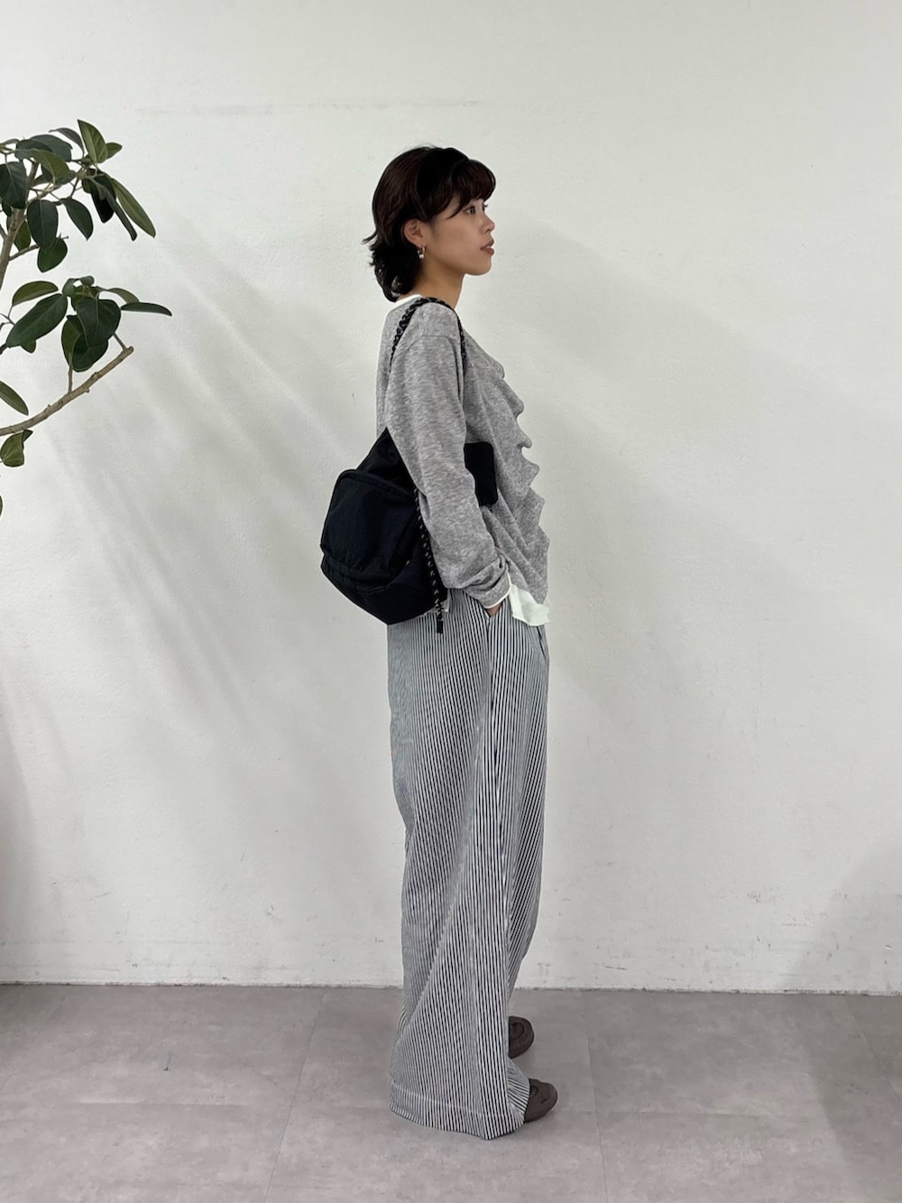 グレー系のカーディガン/ボレロ、ブルー系のデニムパンツ、ブラック系のショルダーバッグを着用したレディースの春コーディネートの2枚目の写真