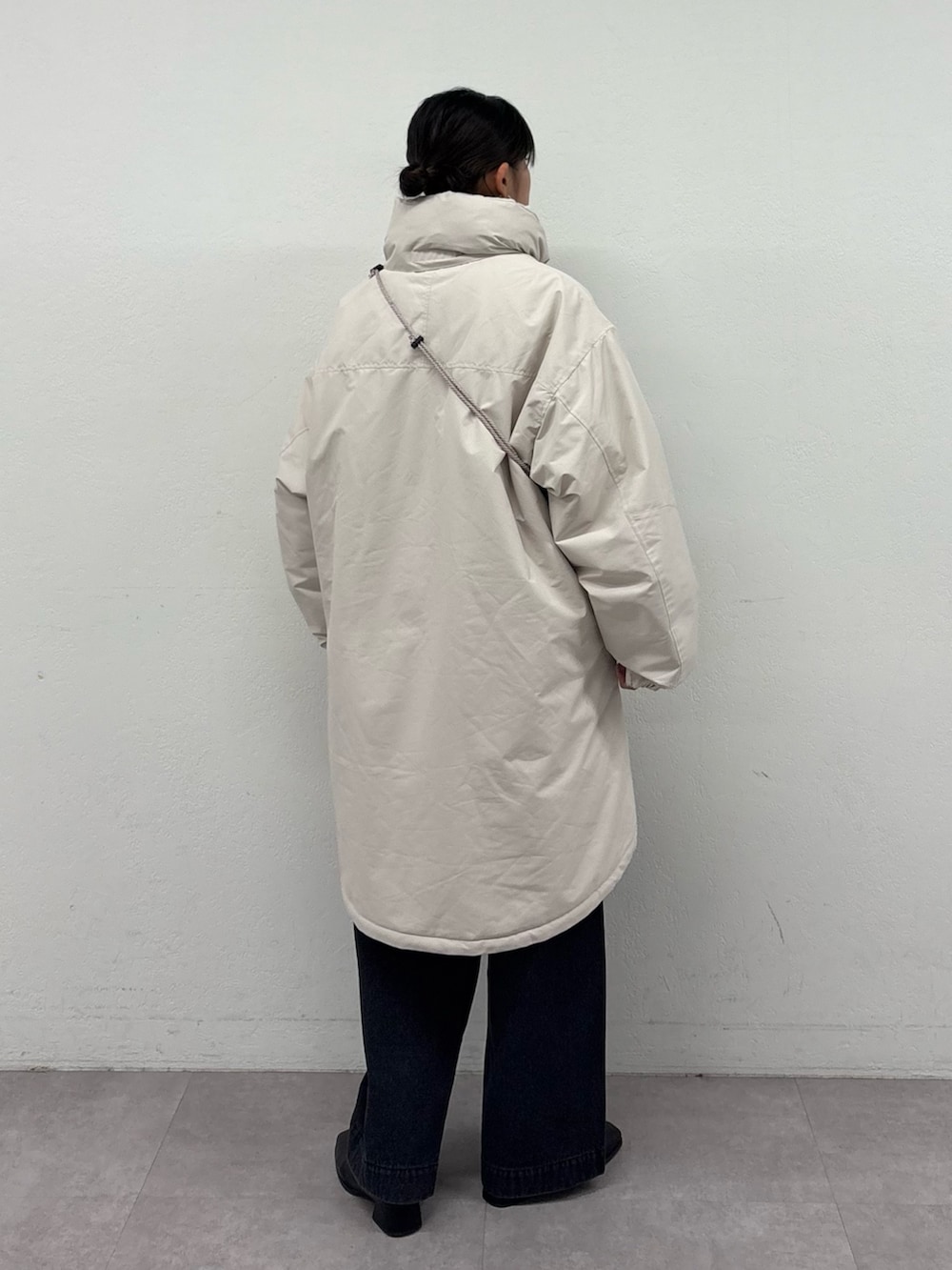 ブラック系のデニムパンツ、ブラック系のブーツ、ホワイト系のダウンジャケット/コートを着用したレディースの冬コーディネートの3枚目の写真