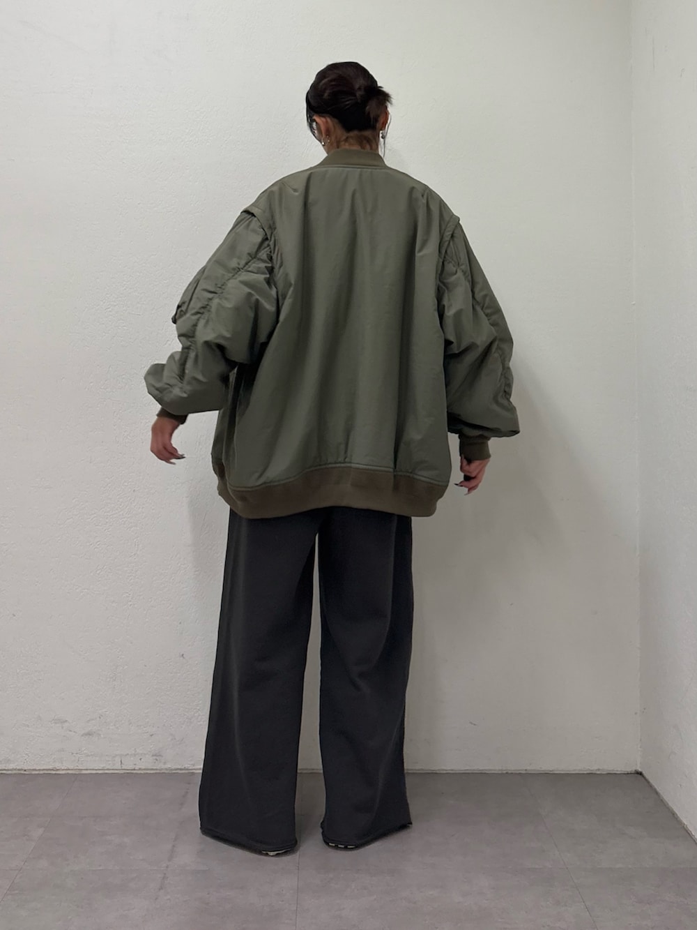 グリーン系のMA-1、ブルー系のニット/セーター、グレー系のスウェットパンツを着用したレディースの冬コーディネートの3枚目の写真