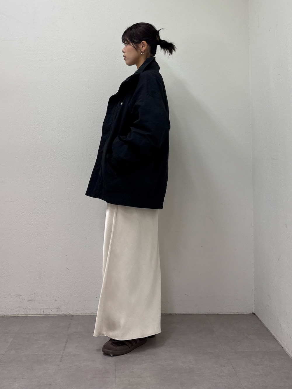 ブラック系のナイロンジャケット、グレー系のスウェット、ホワイト系のスカートを着用したレディースの冬コーディネートの2枚目の写真