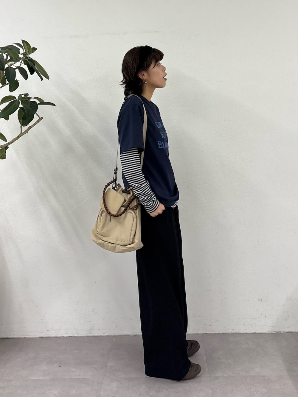 ブルー系のTシャツ/カットソー、ブラック系のスラックス、ベージュ系のトートバッグを着用したレディースの春コーディネートの3枚目の写真