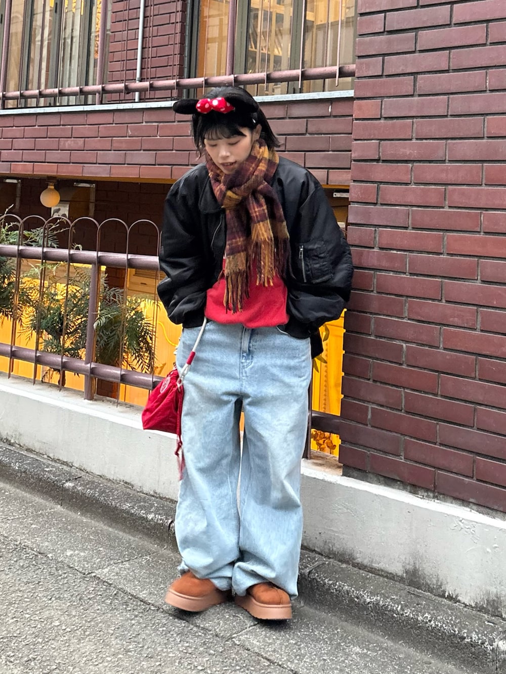 レッド系のスウェット、ブルー系のデニムパンツ、レッド系のショルダーバッグを着用したレディースの秋コーディネートの3枚目の写真