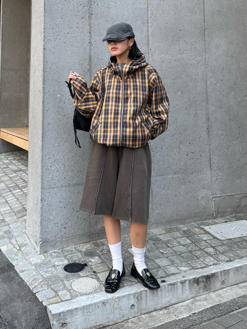 イエロー系のブルゾン、ブラウン系のスウェットパンツ、ブラック系のショルダーバッグを着用したレディースの夏コーディネートの2枚目の写真