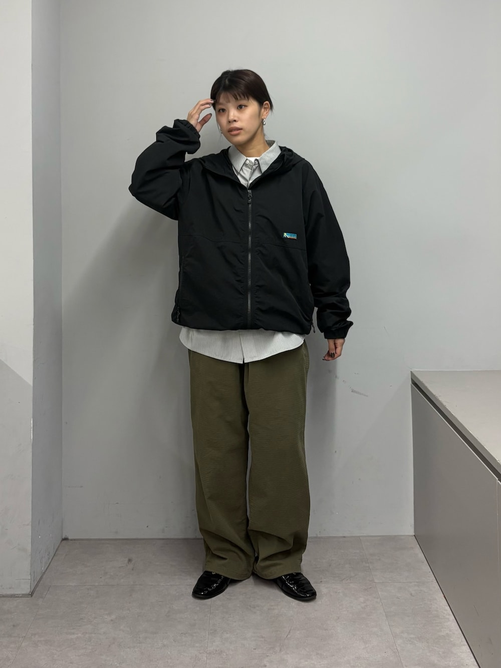 グリーン系のその他パンツ、ブラック系のマウンテンパーカー、グレー系のシャツ/ブラウスを着用したレディースの春コーディネートの2枚目の写真