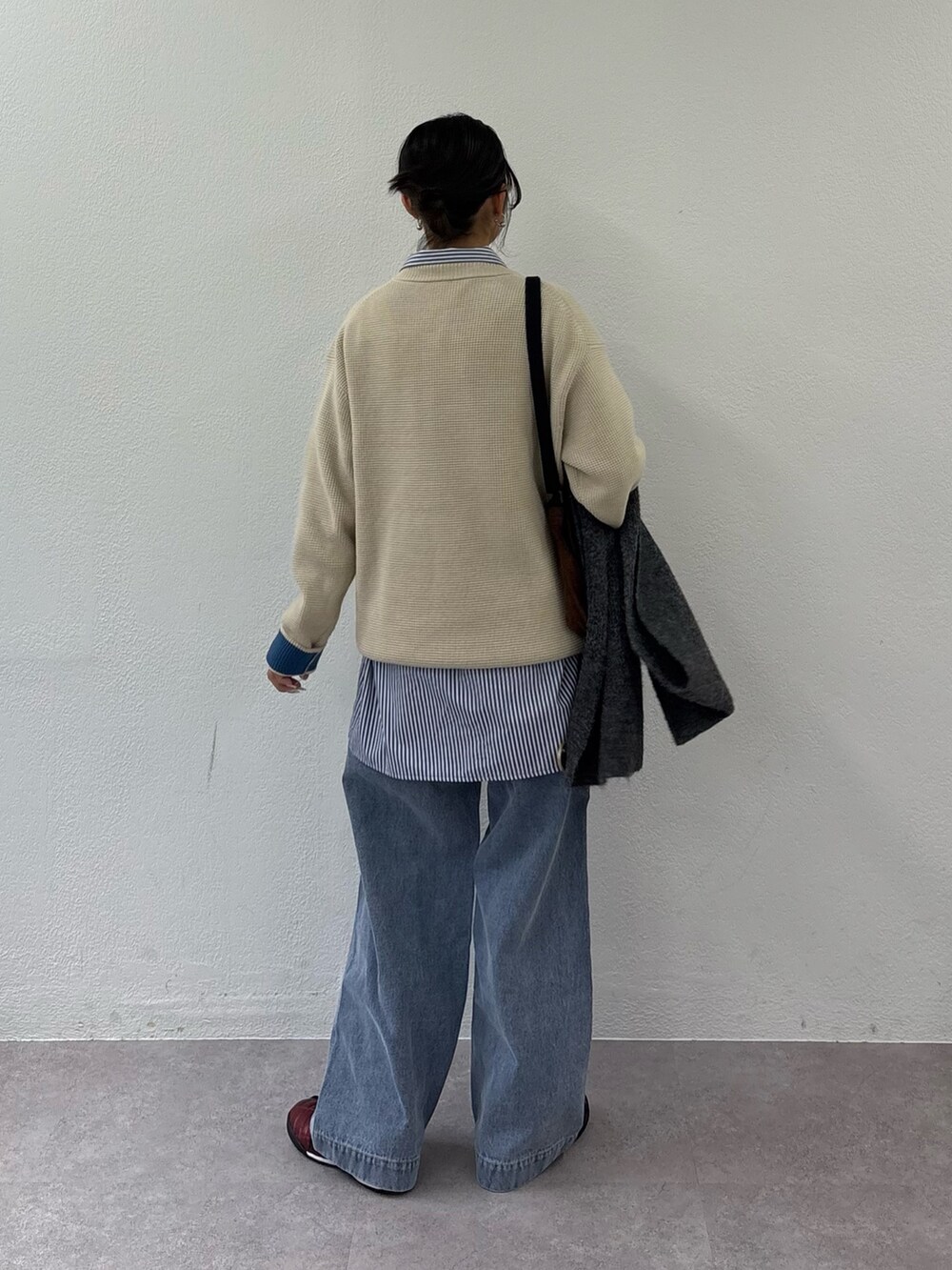 ブルー系のデニムパンツ、ホワイト系のニット/セーター、ブラック系のショルダーバッグを着用したレディースの秋コーディネートの3枚目の写真