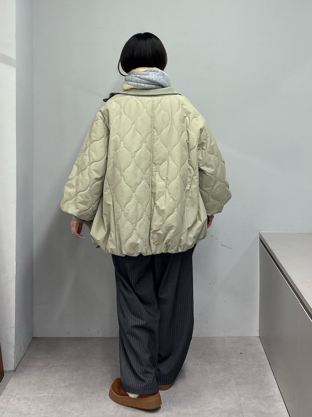 グリーン系のブルゾン、グレー系のスラックス、ブラウン系のトートバッグを着用したレディースの冬コーディネートの3枚目の写真