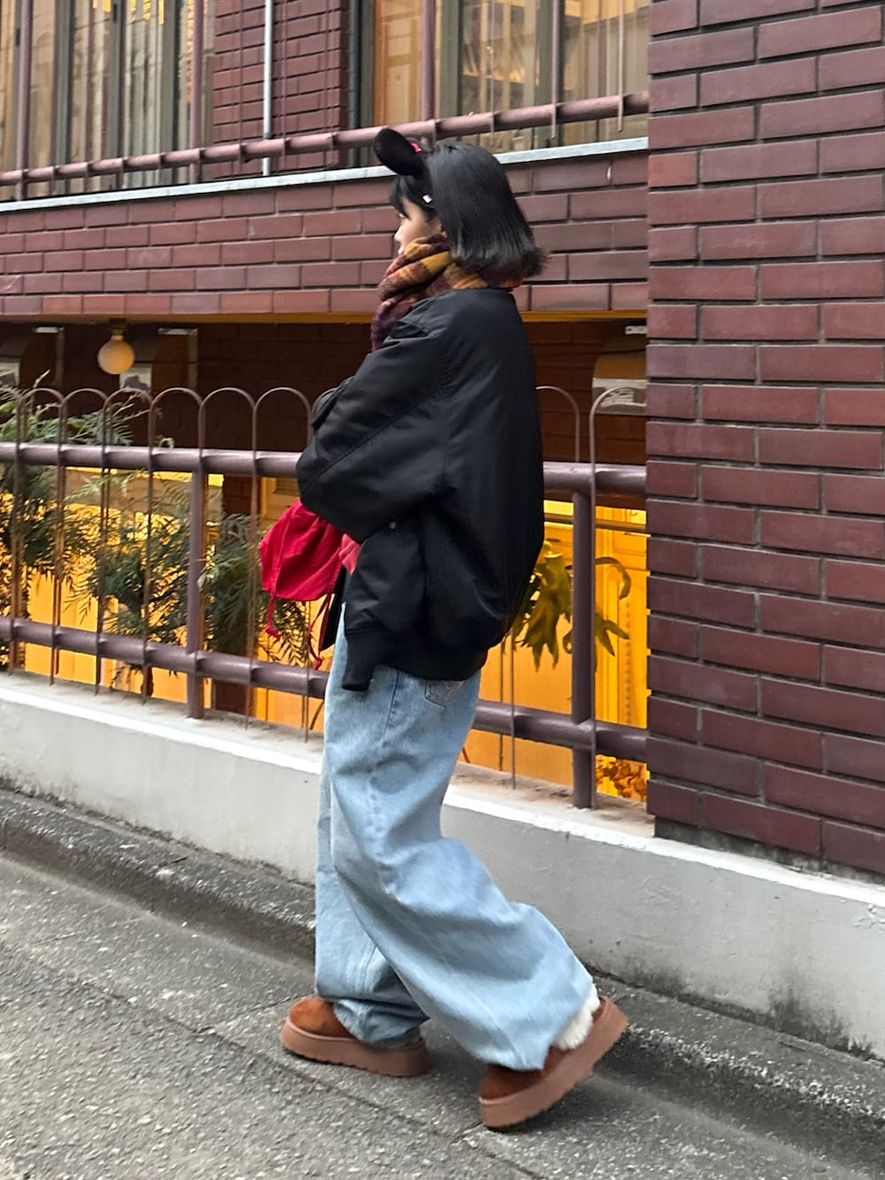 レッド系のスウェット、ブルー系のデニムパンツ、レッド系のショルダーバッグを着用したレディースの秋コーディネートの4枚目の写真