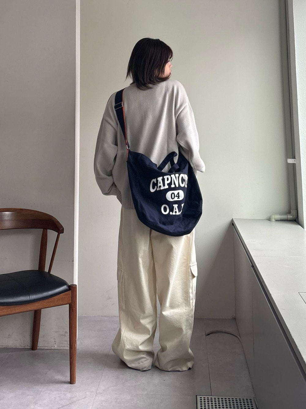 グレー系のニット/セーター、ホワイト系のカーゴパンツ、ブルー系のショルダーバッグを着用したレディースの春コーディネートの4枚目の写真