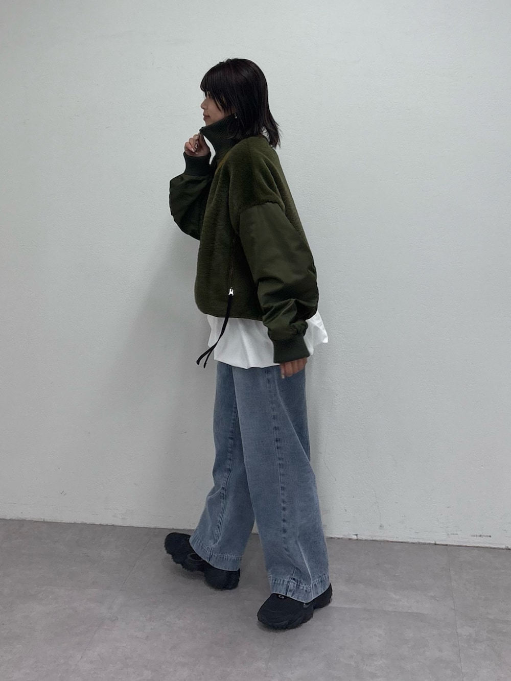 グリーン系のミリタリージャケット、ホワイト系のTシャツ/カットソー、ブルー系のデニムパンツを着用したレディースの冬コーディネートの3枚目の写真