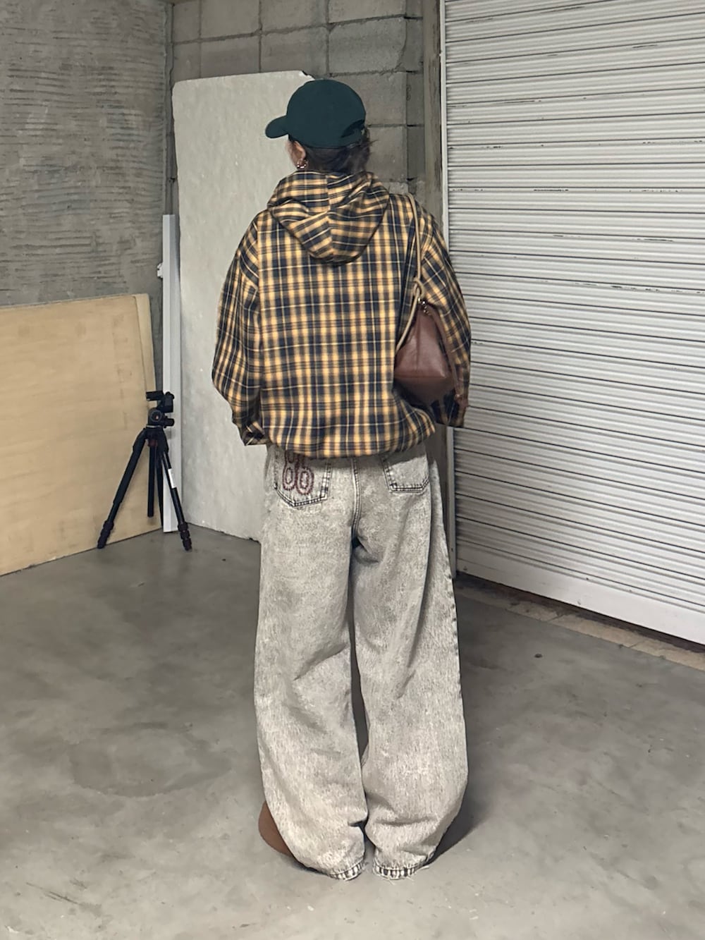 ブラック系のデニムパンツ、ブラウン系のサンダル、イエロー系のブルゾンを着用したレディースの冬コーディネートの4枚目の写真