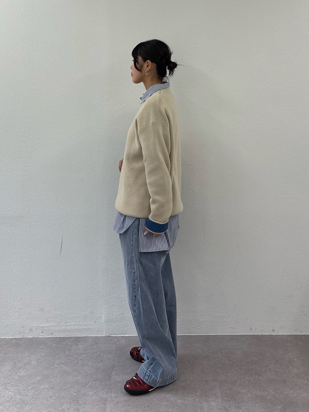 ブルー系のデニムパンツ、ホワイト系のニット/セーター、ブラック系のショルダーバッグを着用したレディースの秋コーディネートの2枚目の写真