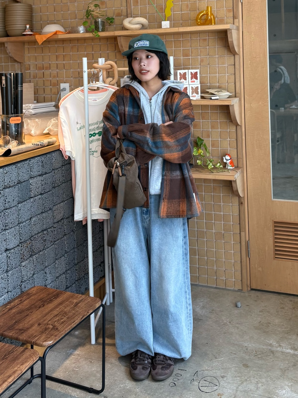 オレンジ系のシャツ/ブラウス、グレー系のパーカー、ブルー系のデニムパンツを着用したレディースの秋コーディネートの2枚目の写真