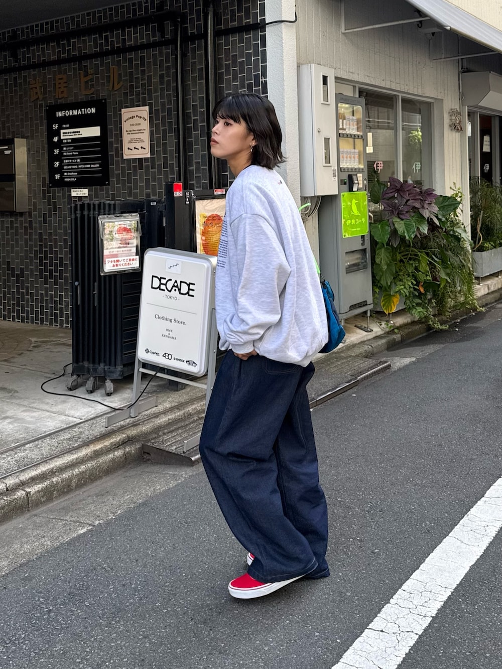 グレー系のスウェット、ブルー系のデニムパンツ、ブルー系のショルダーバッグを着用したレディースの秋コーディネートの2枚目の写真