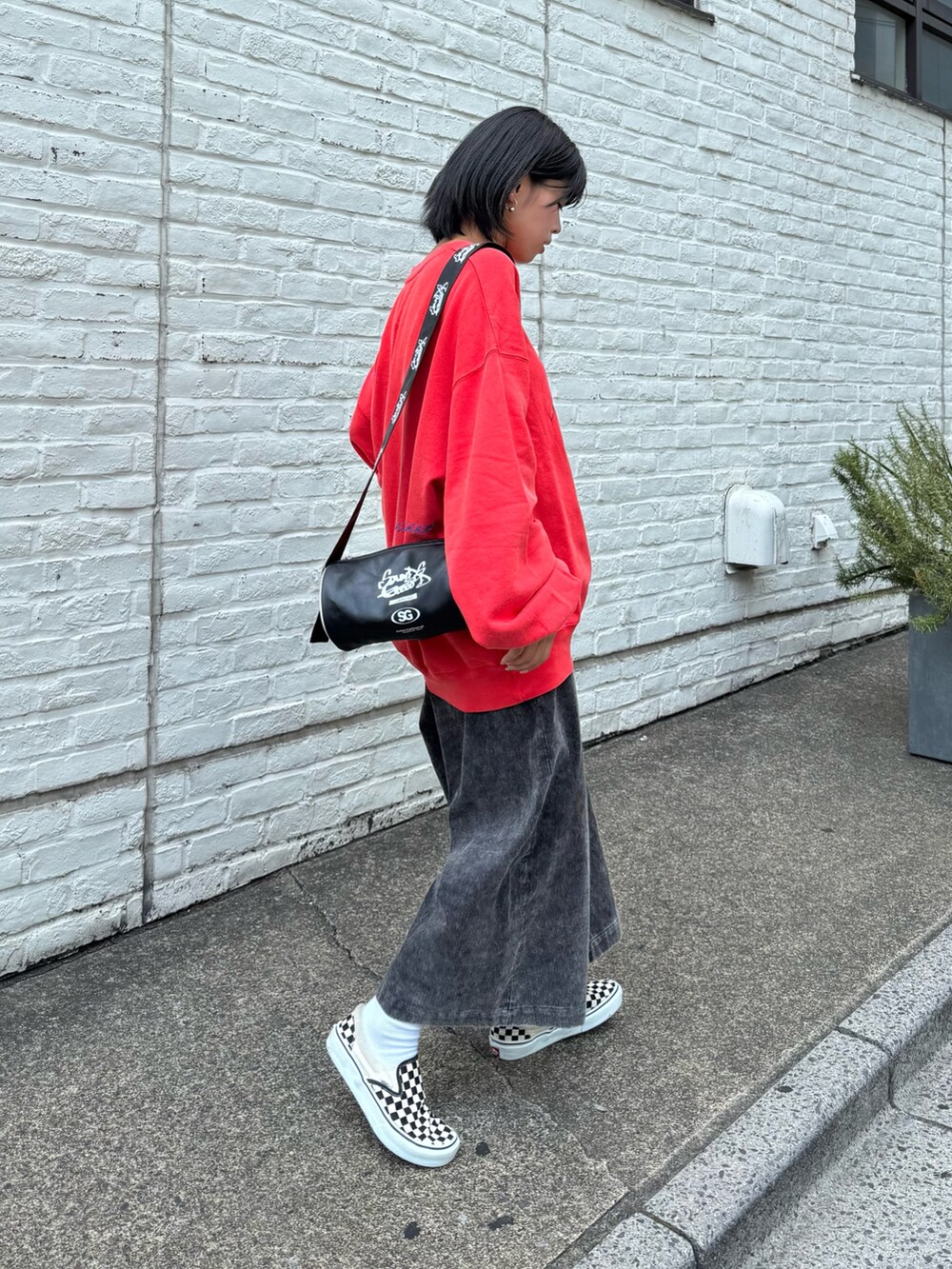 レッド系のスウェット、ブラック系のその他パンツ、ブラック系のボストンバッグを着用したレディースの秋コーディネートの2枚目の写真