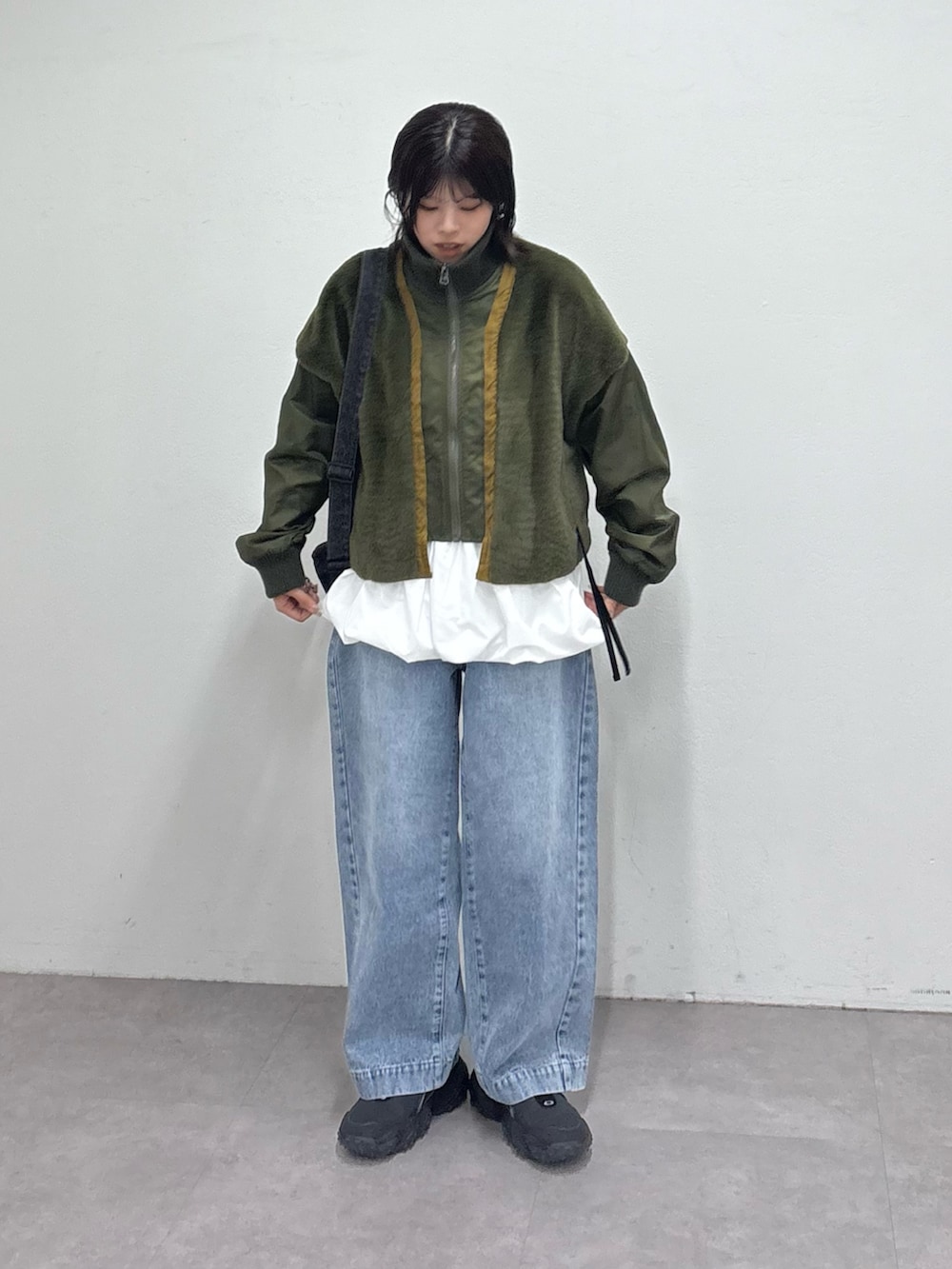 グリーン系のミリタリージャケット、ホワイト系のTシャツ/カットソー、ブルー系のデニムパンツを着用したレディースの冬コーディネートの2枚目の写真