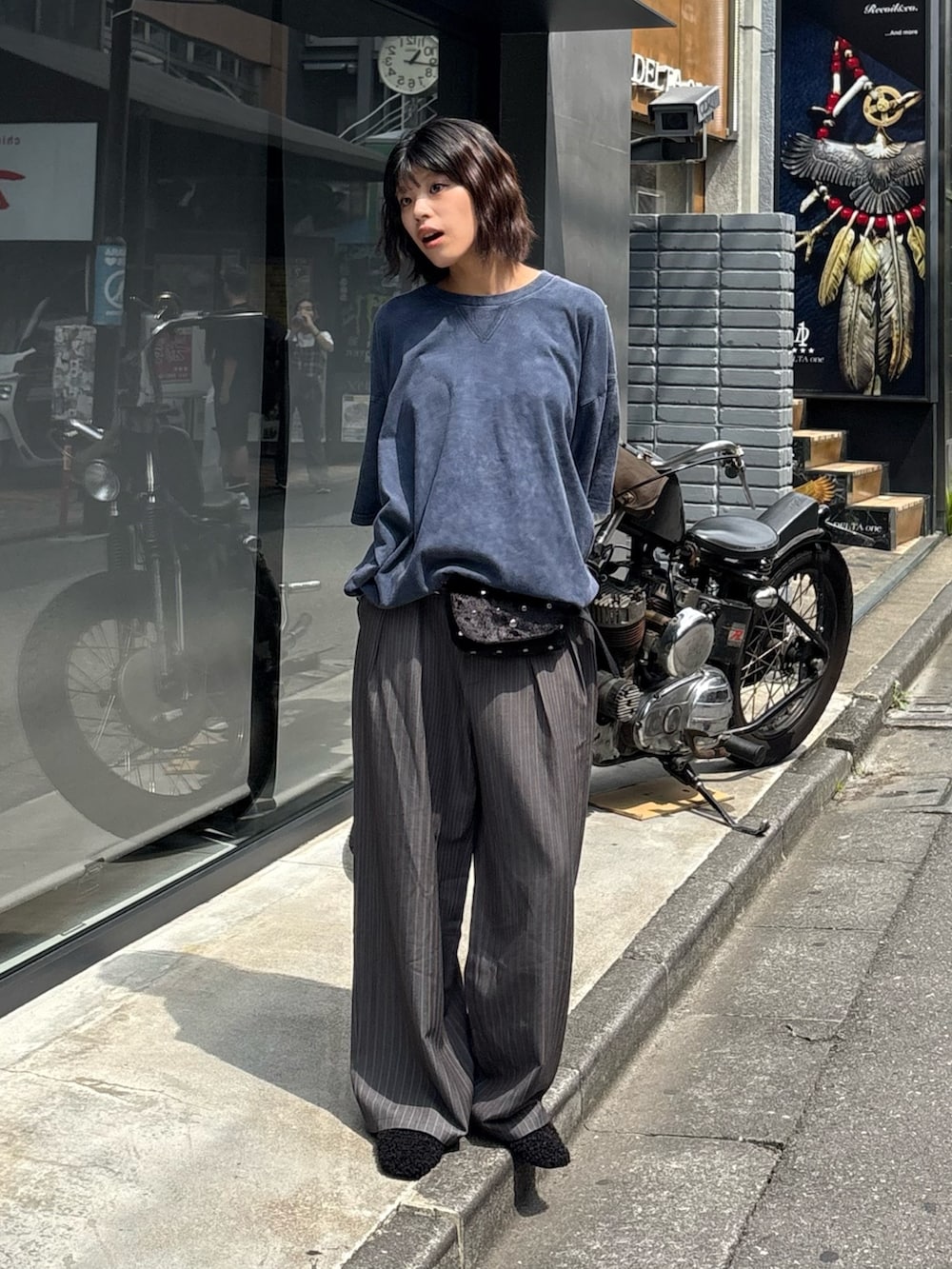 ブルー系のTシャツ/カットソー、グレー系のスラックス、ブラック系のボディバッグ/ウエストポーチを着用したレディースの秋コーディネートの2枚目の写真
