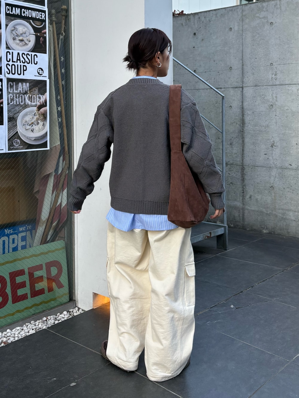 グレー系のカーディガン/ボレロ、ホワイト系のデニムパンツ、ブラウン系のトートバッグを着用したレディースの冬コーディネートの3枚目の写真