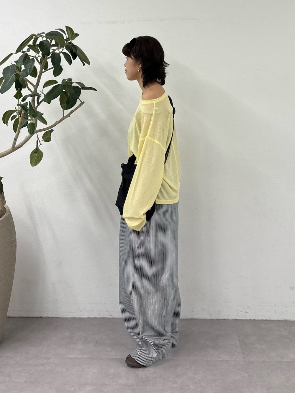 ブルー系のデニムパンツ、イエロー系のTシャツ/カットソー、ブラック系のショルダーバッグを着用したレディースの春コーディネートの2枚目の写真