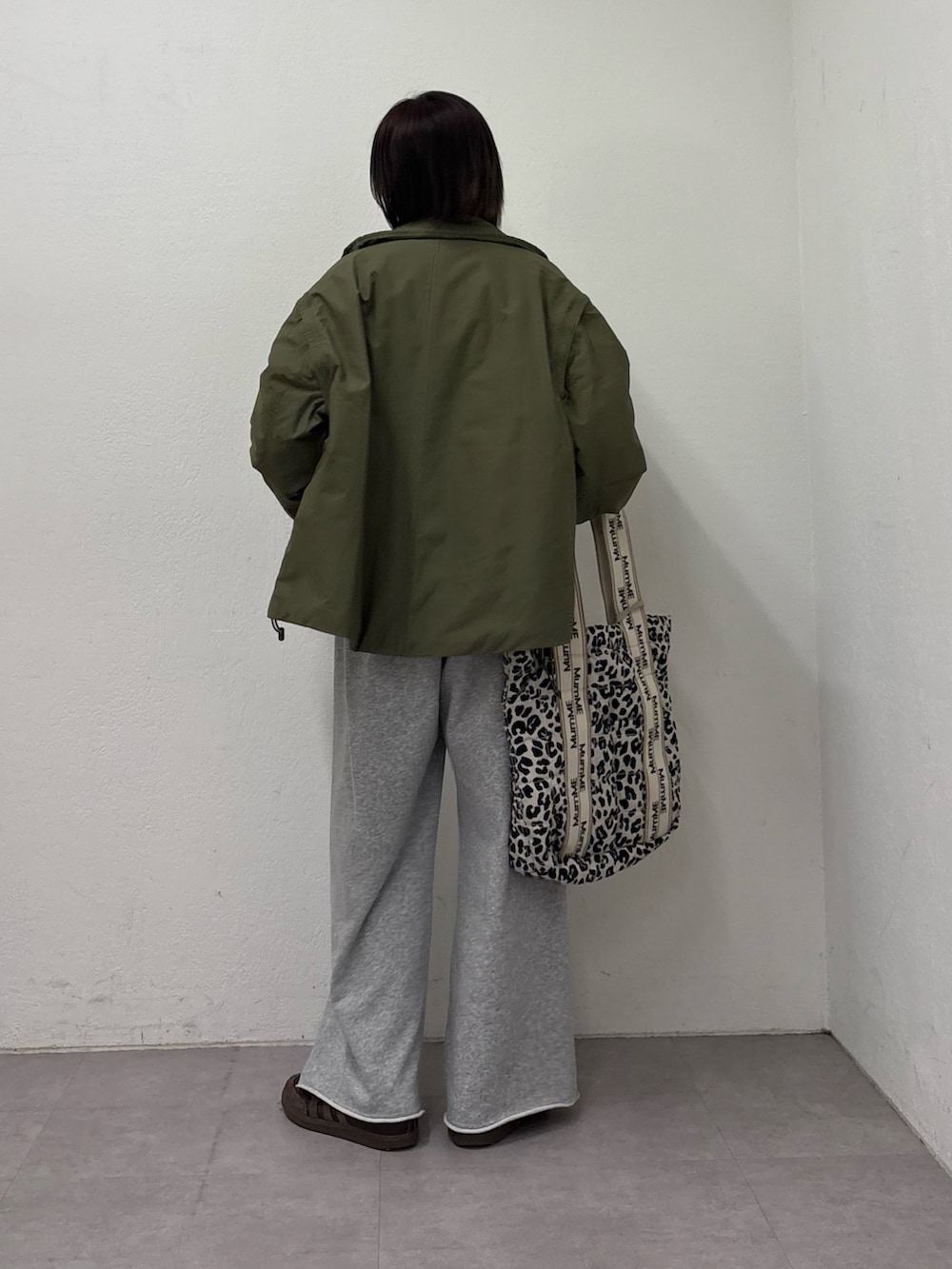 グリーン系のブルゾン、グレー系のスウェットパンツ、イエロー系のニット/セーターを着用したレディースの冬コーディネートの3枚目の写真