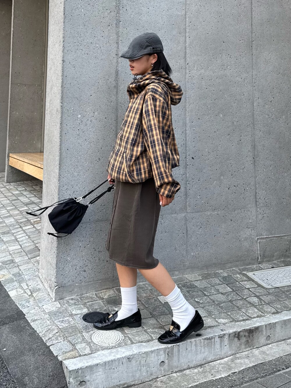 イエロー系のブルゾン、ブラウン系のスウェットパンツ、ブラック系のショルダーバッグを着用したレディースの夏コーディネートの3枚目の写真