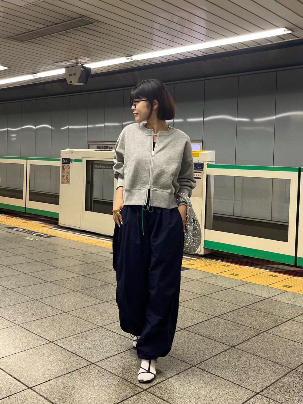 ブラック系のサンダル、ブルー系のパンツ、シルバー系のハンドバッグを着用したレディースの春コーディネートの3枚目の写真
