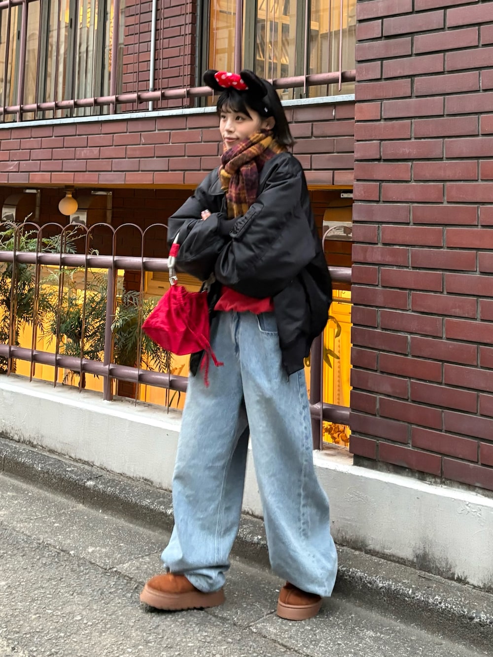 レッド系のスウェット、ブルー系のデニムパンツ、レッド系のショルダーバッグを着用したレディースの秋コーディネートの2枚目の写真