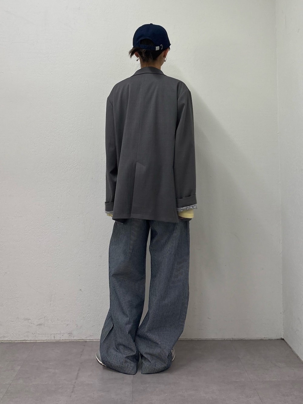 グレー系のテーラードジャケット、イエロー系のTシャツ/カットソー、ブルー系のデニムパンツを着用したレディースの冬コーディネートの4枚目の写真