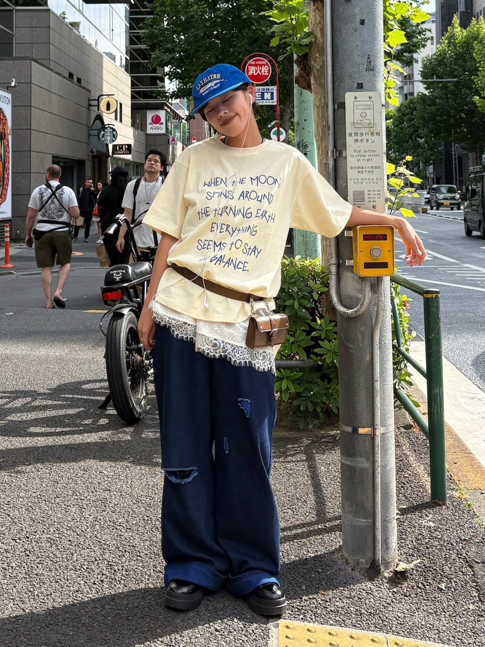 ベージュ系のTシャツ/カットソー、ブルー系のデニムパンツ、ホワイト系のスカートを着用したレディースの春コーディネートの2枚目の写真
