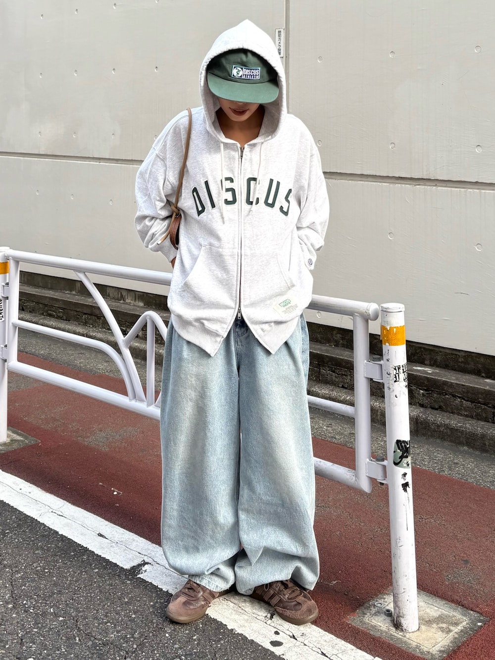 グレー系のパーカー、ブルー系のデニムパンツ、ブラウン系のショルダーバッグを着用したレディースの秋コーディネートの2枚目の写真