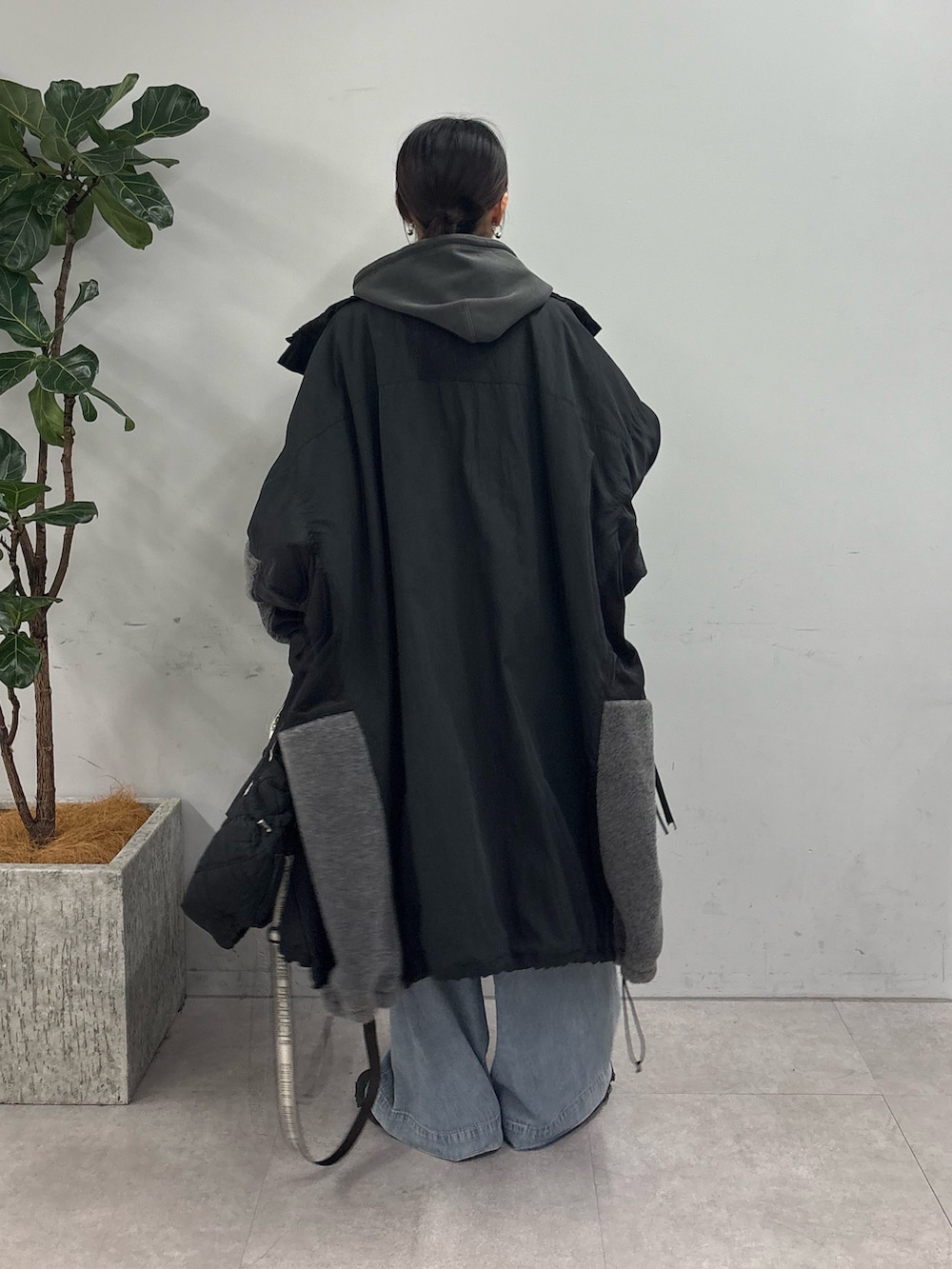 グレー系のパーカー、ブラック系のモッズコート、ブルー系のデニムパンツを着用したレディースの秋コーディネートの3枚目の写真