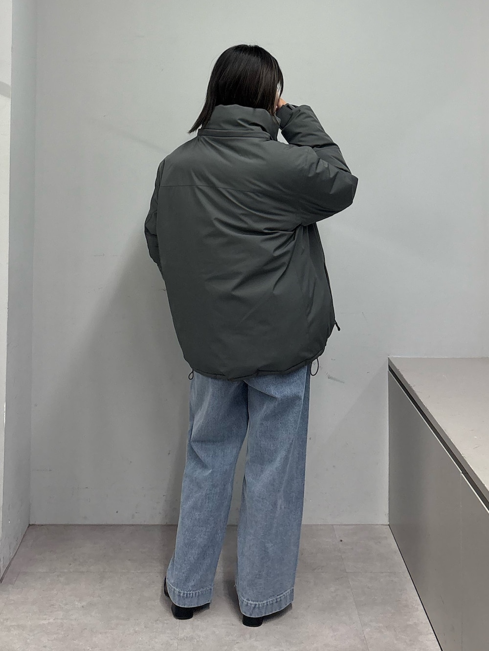 グレー系のダウンジャケット/コート、ブラック系のニット/セーター、ブルー系のデニムパンツを着用したレディースの冬コーディネートの3枚目の写真