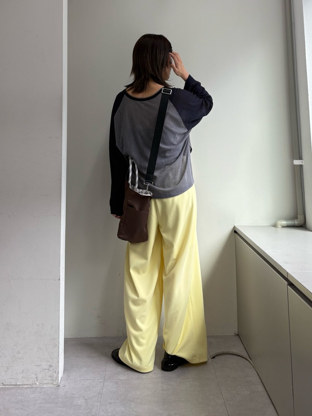 グレー系のTシャツ/カットソー、イエロー系のスラックス、ブラウン系のショルダーバッグを着用したレディースの春コーディネートの3枚目の写真