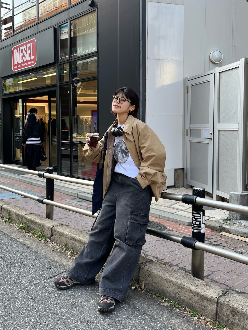 ブラック系のカーゴパンツ、ブルー系のトートバッグ、ベージュ系のブルゾンを着用したレディースの春コーディネートの2枚目の写真