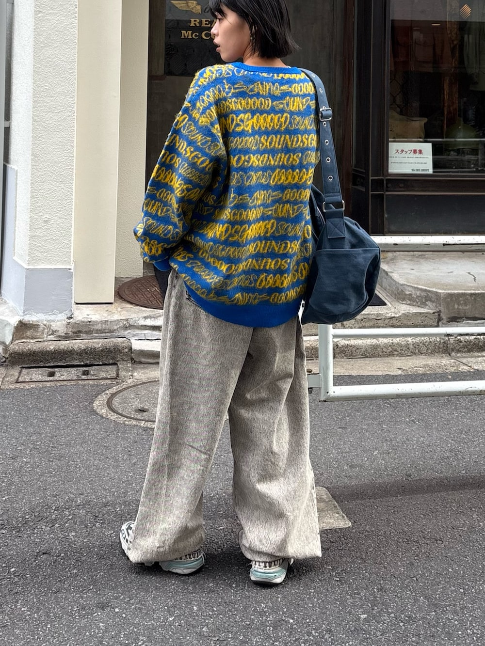 イエロー系のニット/セーター、ブラック系のデニムパンツ、ブルー系のトートバッグを着用したレディースの秋コーディネートの3枚目の写真