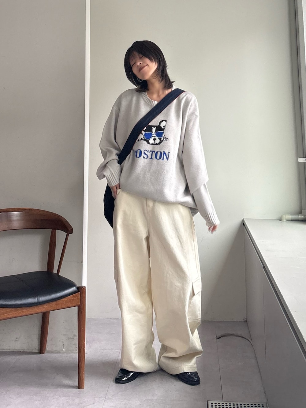 グレー系のニット/セーター、ホワイト系のカーゴパンツ、ブルー系のショルダーバッグを着用したレディースの春コーディネートの2枚目の写真